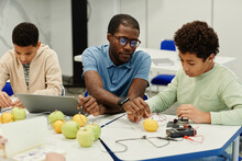 Portrait Of African-American Teacher Working On Science Experiments With Diverse Group Of Children