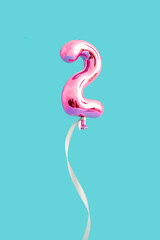 Number two shape made with pink balloon and ribbon against bright blue background. Anniversary concept. Creative idea of Love or valentine days.