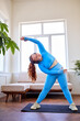 © Roman - overweight female doing stretching exercises at home, in blue sportswear. fat caucasian lady with natural red hair lead intense weight loss slimming healthy fitness program, engaged in sport
