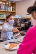 © Sangiao_Photography - Latin young woman serving a coffee in a bistro to an senior adult Hispanic man. Peruvian restaurant