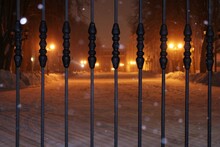 Yellow Lanterns, Metal Fence And Snow In The Park At Winter Night