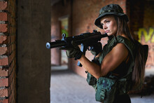 Beautiful and attractive female army soldier posing with gun rifle weapon. Woman with weapon. Firearm shooting range gun shooting training in abandoned building. Caucasian lady is fighting with enemy
