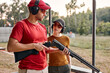 © Roman - handsome confident man teach woman to recharge a rifle on shooting range outdoors, give instructions and have talk, wearing protective headset, spectacles and cap, holding rifle in hands.