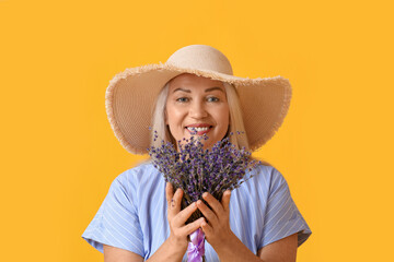 Wall Mural - Portrait of beautiful mature woman with bouquet of flowers on color background