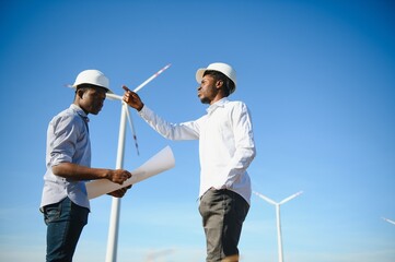 Young maintenance engineer team working in wind turbine farm at sunset stock photo