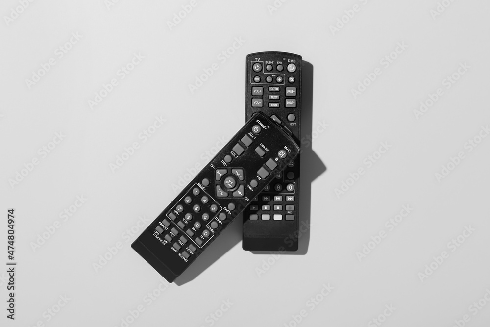 Black TV remote controllers on grey background