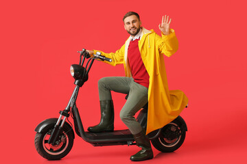 Canvas Print - Young man in raincoat and with bike on color background