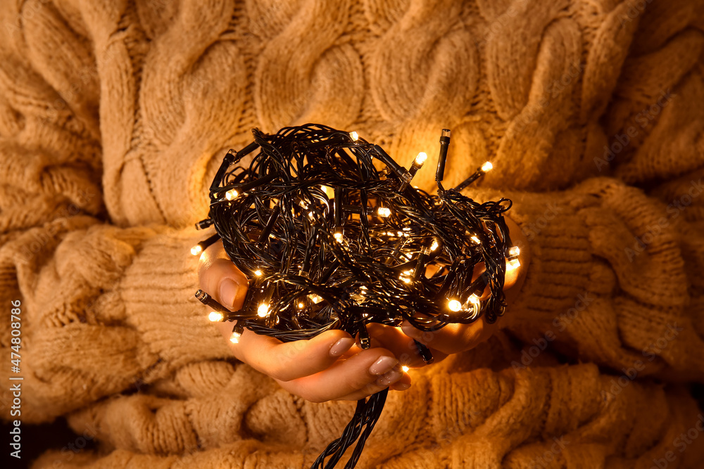 Woman holding beautiful Christmas lights, closeup