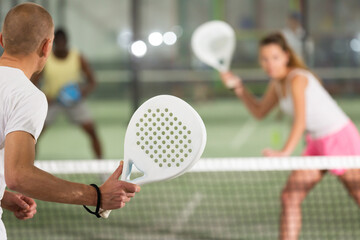 Wall Mural - Padel player playing padel in a padel court indoor behind the net