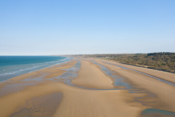  The immense fine sand beach of Omaha beach in Europe, in France, in Normandy, towards Arromanches, in Colleville, in spring, on a sunny day.