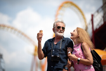 elderly senior couple woman and man having fun and happy together at amusement them park