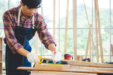 young carpenter Asian man, wooden maker craftsman working with a industry carpentry tool workshop