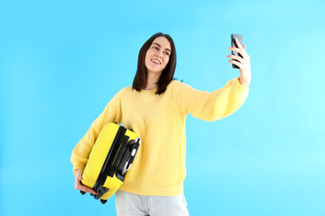 Poster - Woman with travel bag doing selfie on blue background