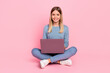 Leinwandbild Motiv Full body photo of young girl use laptop sit floor homework courses type isolated over pink color background