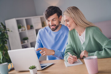 Wall Mural - Portrait of two attractive cheerful people using laptop choosing order goods web service at home indoors