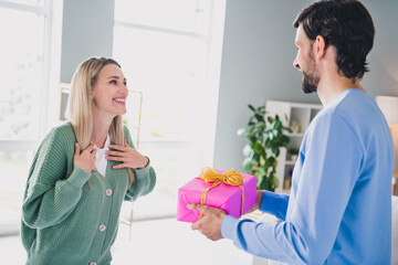 Wall Mural - Portrait of two attractive cheerful careful sweet people guy handling giftbox greetings at home indoors