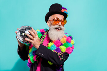 Photo of impressed funky senior hipster wear diy pop-pom blazer holding disco ball empty space smiling isolated teal color background