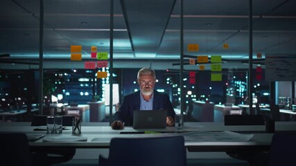 Leinwandbilder - Successful Senior Businessman Working on Laptop Computer in Big City Office Late in the Evening. Investment Analyst Checking Financial Graphs from Project Management Reports. Static Shot.