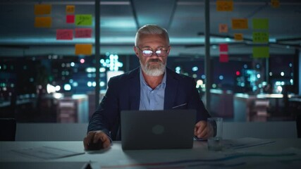 Poster - Successful Senior Businessman Working on Laptop Computer in Big City Office Late in the Evening. Investment Analyst Checking Financial Management Reports, Drinking Water from Glass. Static Shot.