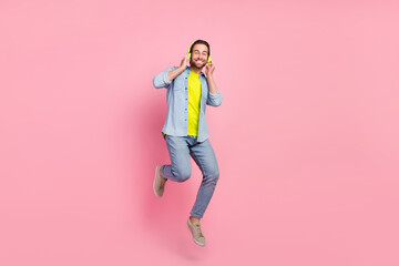 Sticker - Full size photo of young cheerful guy have fun jump listen song playlist earphones isolated over pink color background