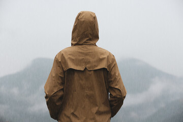 Poster - Woman in raincoat enjoying mountain landscape under rain, back view