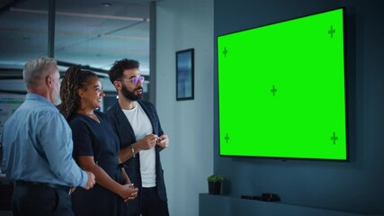 Wall Mural - Company Operations Manager Holds Meeting Presentation for a Team of Executives. Adult Male Uses Wide TV Set with Horizontal Green Screen Mock Up Display. People Work in Business Office.