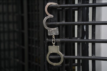 Handcuffs are hanging on the bars of the door of the detention center