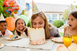 © Drobot Dean - Multiracial children making fun while eating cake during birthday party