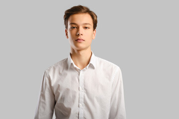 Wall Mural - Portrait of handsome young man in white shirt over grey background