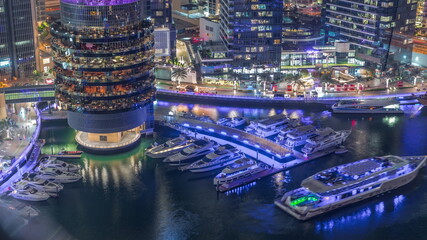 Wall Mural - Dubai marina waterfront and building with different restaurants at each floor aerial night timelapse.