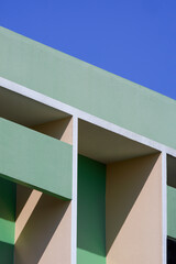 Abstract geometric pattern background of shading fin concrete on modern green and beige building wall against blue clear sky in vertical frame