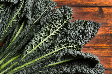 Foglie di cavolo nero fresco su fondo di legno. Cavolo nero. Cibo italiano.