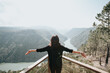 Young beautiful woman traveler looking at beautiful Landscape with a lookout point. Loot of empty sky for your text. Mental health relax and thinking about the future. Freedom, travel, vacation.