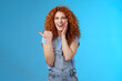 Entertained charismatic good-looking ginger girl curly hairstyle touch cheek gently pleased smiling broadly enthusiastic pointing left thumb impressed excited see awesome promo stunning location