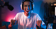 © Urbanscape - Young Asian man playing online computer video game, colorful lighting broadcast streaming live at home. Ecstatic celebration winning a match. Gamer lifestyle, E-Sport online gaming technology concept