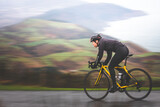 Fototapeta Uliczki - Pan shot of a young caucasian cyclist man sprinting on his bike.
