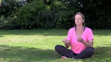 Attractive Happy Middle Aged Woman In Her Forties Outside Cross Legged Practicing Yoga In Prayer