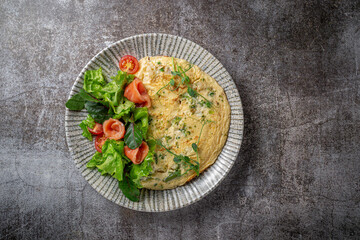 Sticker - Omelet with salmon, fresh herbs and tomatoes in a blue plate with spices against a gray stone table .