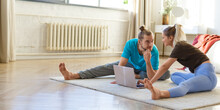 Young Couple Stretching At Home In Front Of A Laptop Monitor. The Concept Of A Healthy Lifestyle And Maintaining Oneself In Shape. Format Photo 2x1.