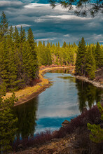 2021-12-14 THE TREE LINED DESCHUTES RIVER NEAR SUNRIVER OREGON AT DUSK WITH A LIGHT BLUE CLOUDY SKY IN LATE NOVEMBER-