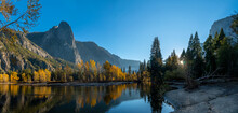Panoramic View Of Fall Season Color Trees Reflected On Water With Mountains In The Background