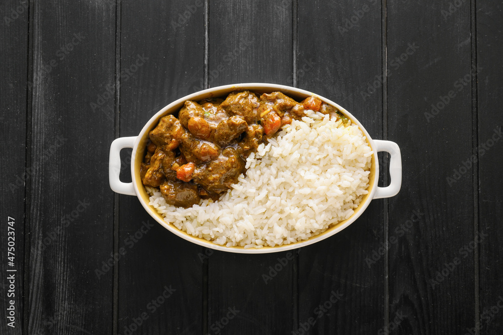 Dish with tasty beef curry on dark wooden background