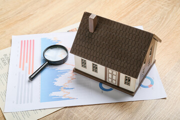 Poster - House model with magnifier and diagrams on wooden background