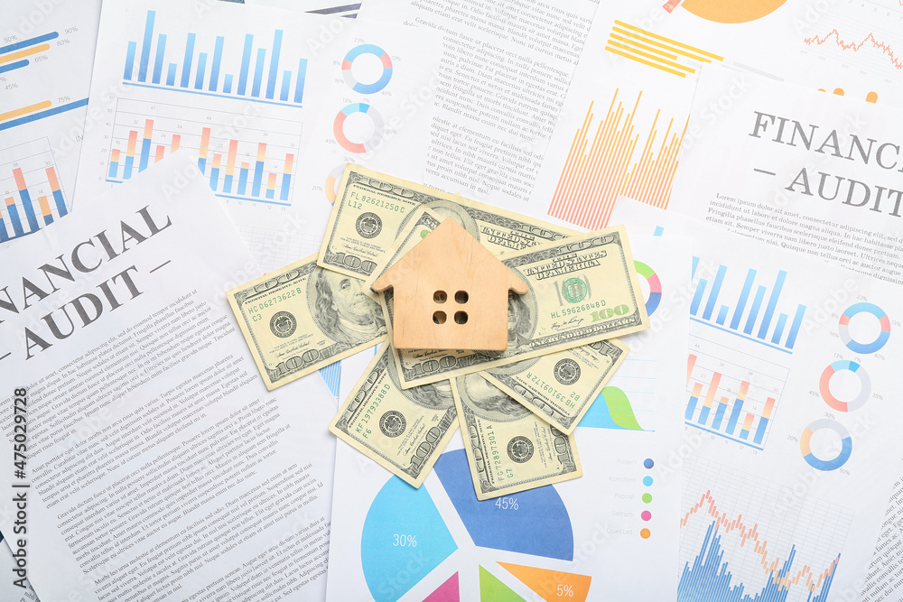 Wooden house and dollar banknotes on paper sheets with diagrams