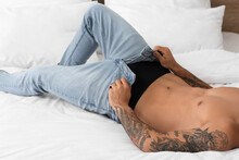 Sexy Young Man Taking Off His Jeans In Bedroom