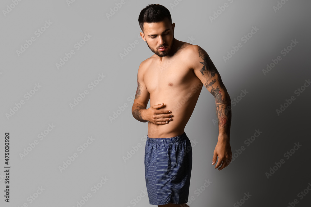 Handsome young man in underwear on grey background