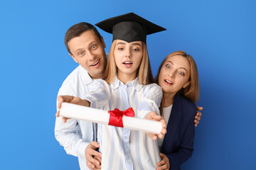 Wall Mural - Surprised female graduation student with her parents on color background