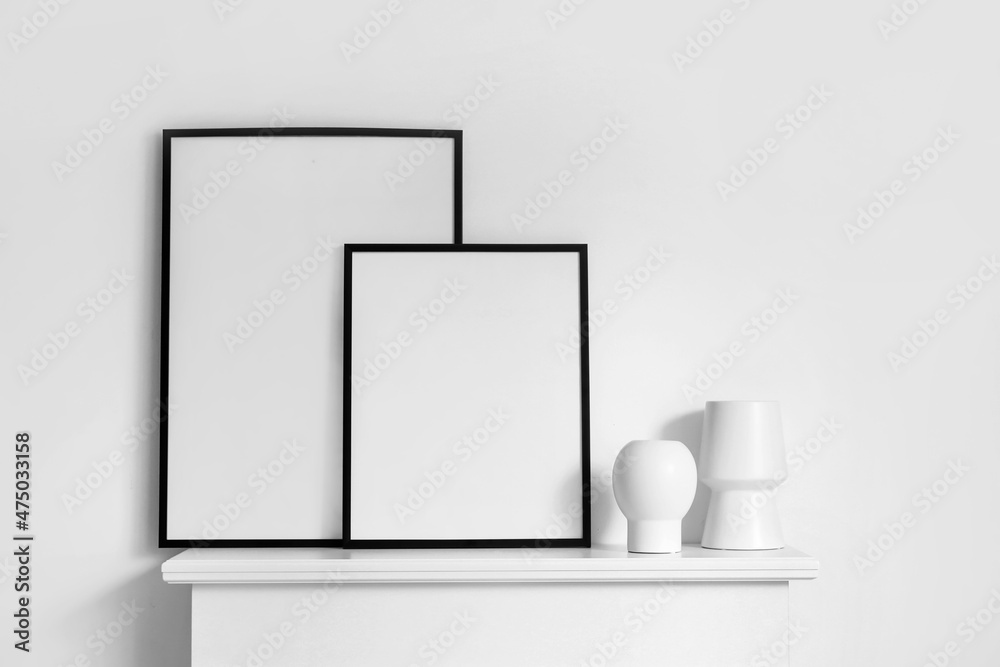 Fireplace with blank poster frames in light bedroom