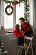 Two brothers Watching the snow fall through a window in festively decorated room. Waiting For Santa