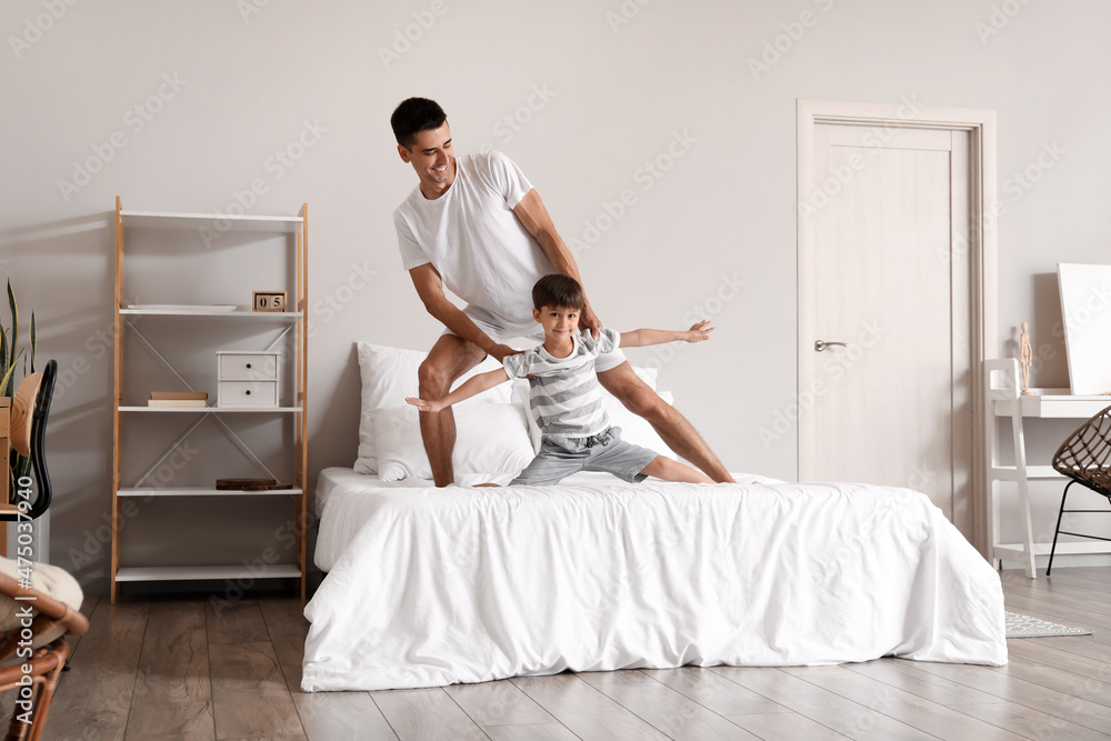 Man and his little son dancing in bedroom